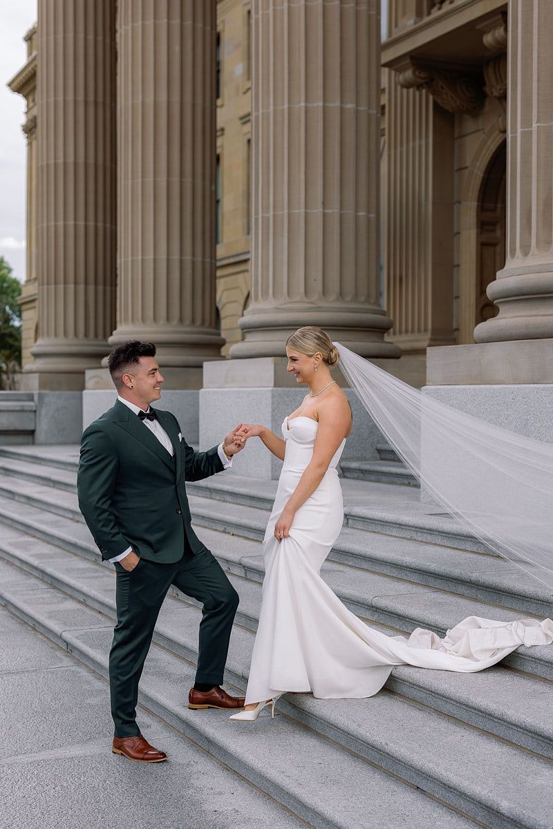 Groom guiding bride down stairs, tender Riga wedding moment