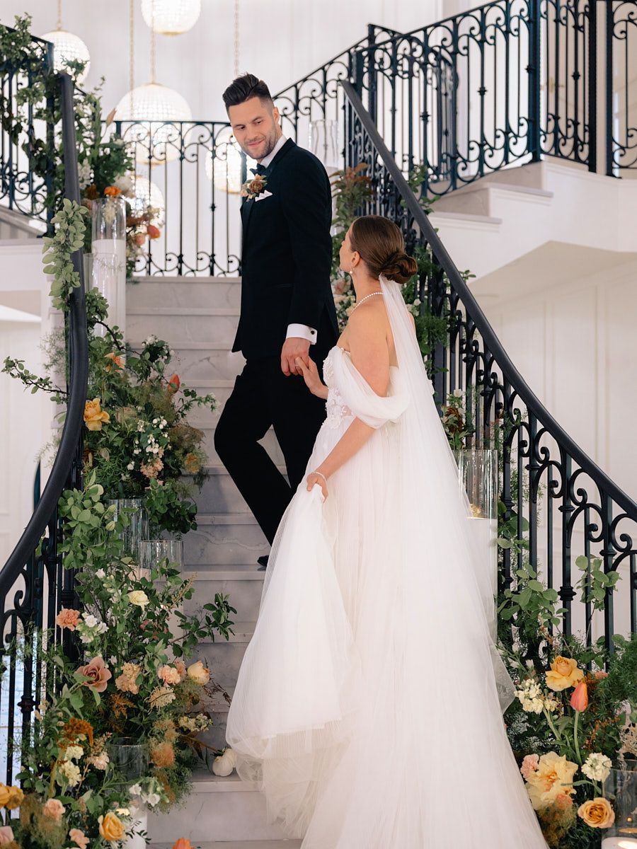 Newlyweds posing on floral stairs, sophisticated Riga wedding photography