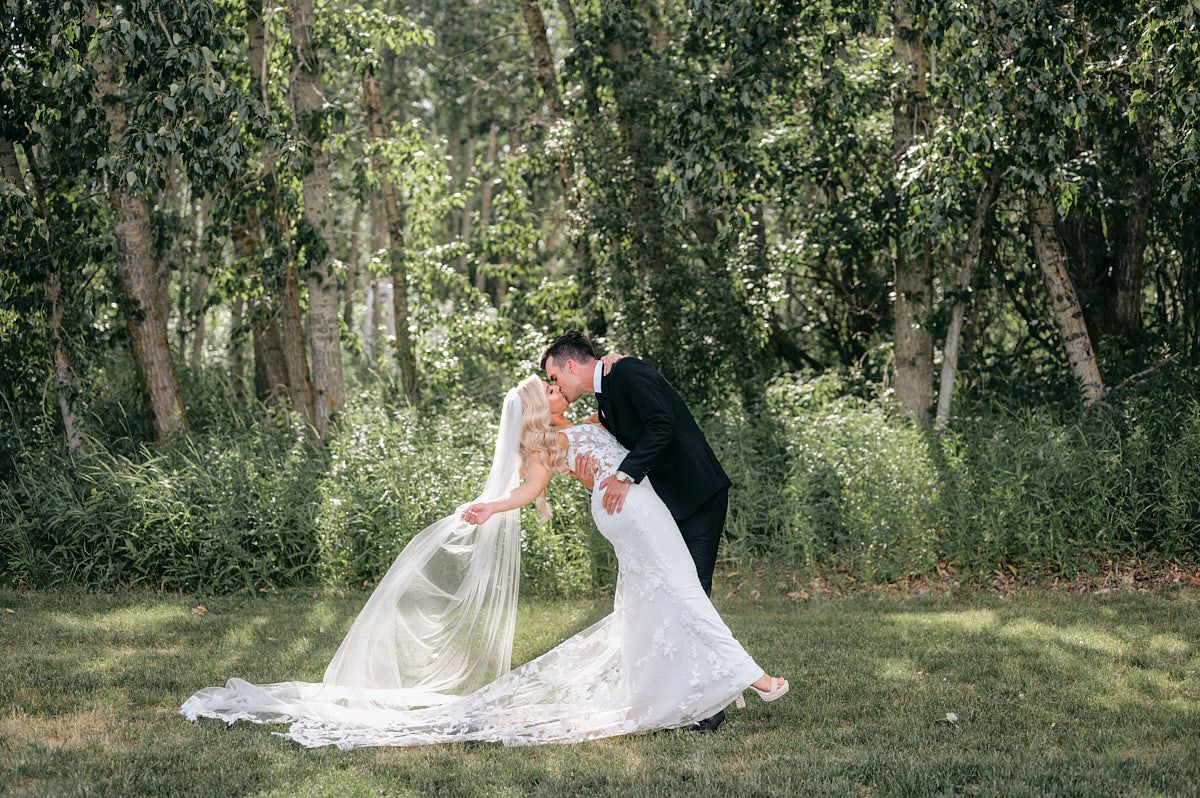 The couple shares a  passionate kiss, surrounded by lush green landscapes in the forest in Riga