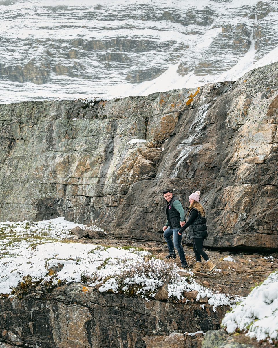Engaged couple walking through snowy landscape, winter engagement session in Europe