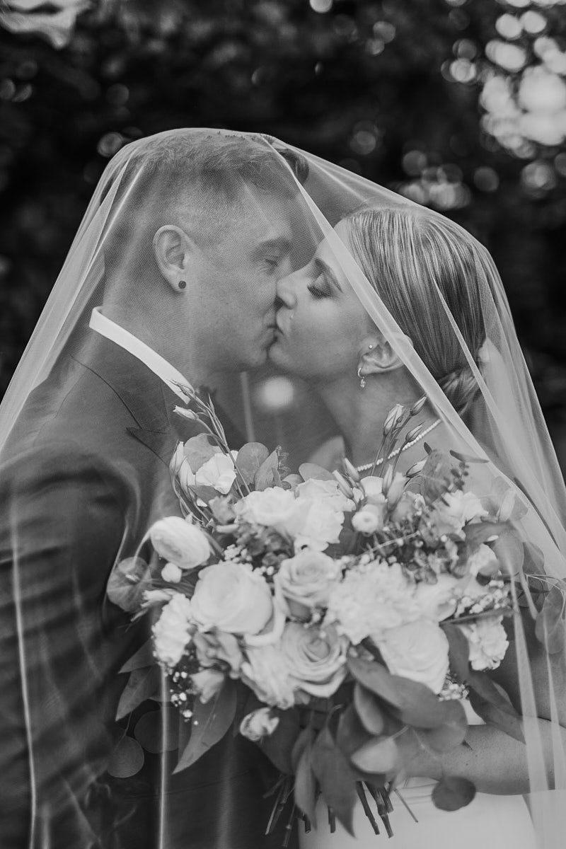 Bride and groom kissing under the veil during intimate Riga wedding ceremony