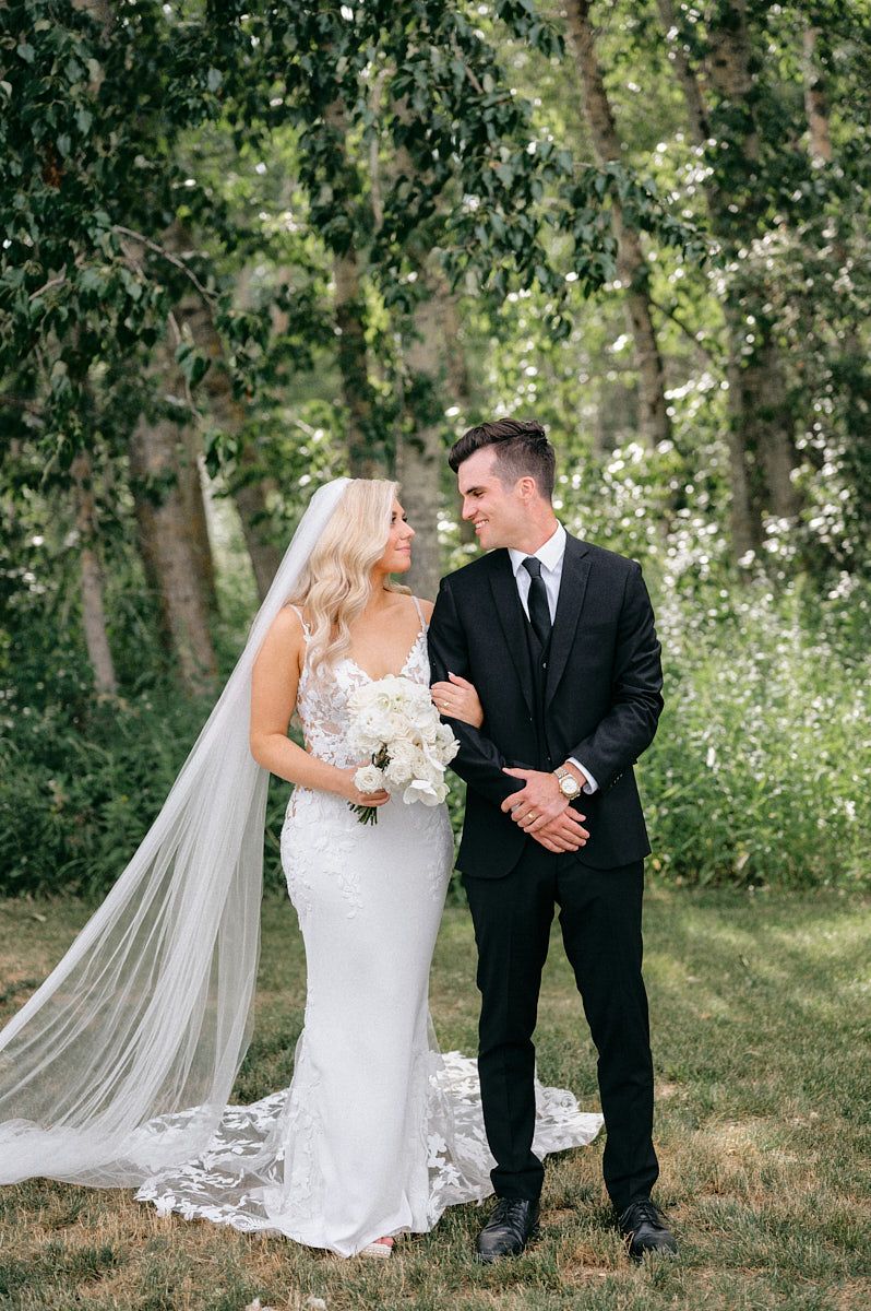 The bride and groom share an intimate embrace on the scenic grounds of a Latvian wedding venue.