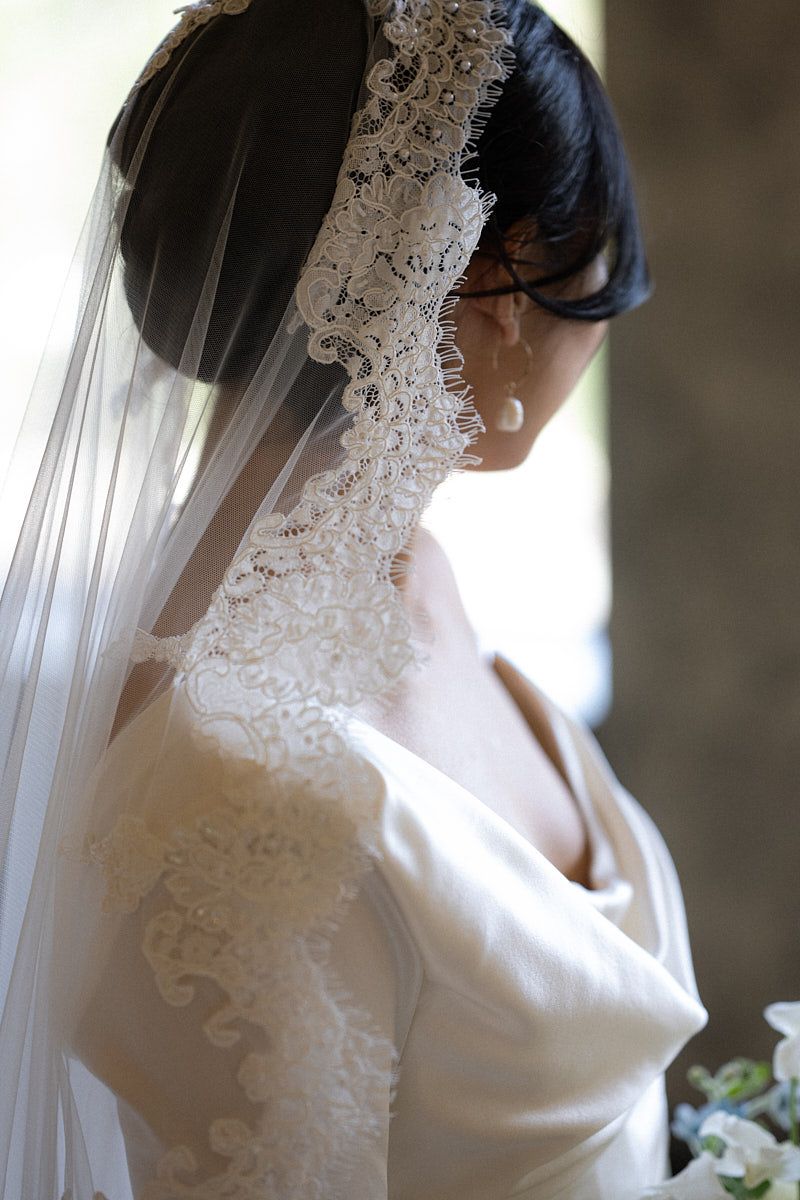 Bride showcasing delicate Spanish veil in a romantic European wedding setting
