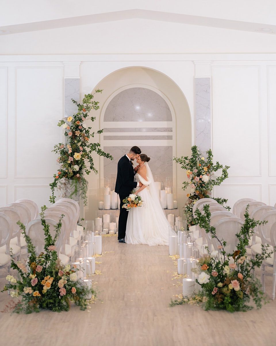 Bride and groom standing under arch with glowing candles, intimate Riga wedding ceremony moment