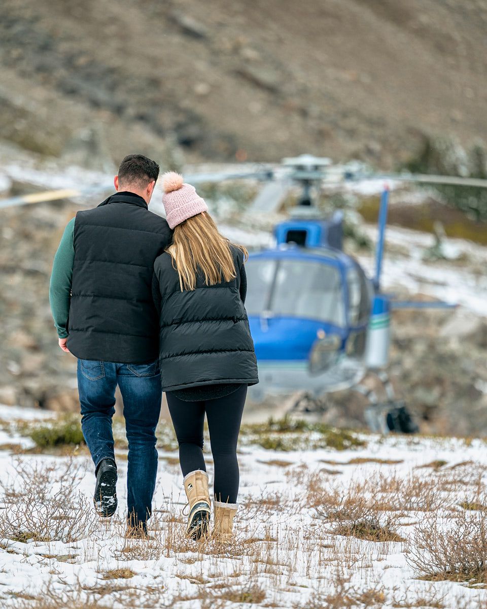 Engaged couple walking toward helicopter, luxury engagement session in Europe