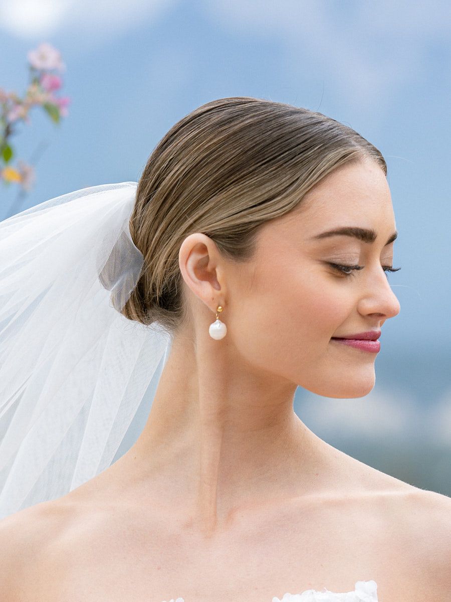 Playful bridal portrait with bride adjusting veil, captured in soft Riga wedding light