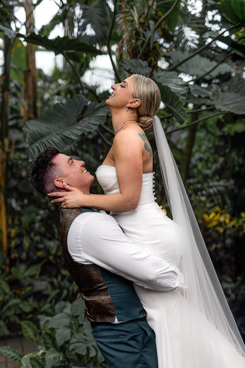 Groom lifting laughing bride during joyful Riga wedding portrait session