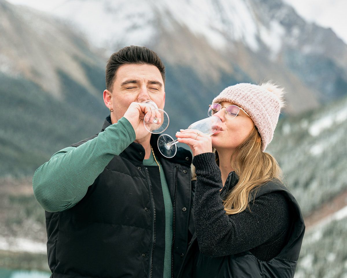 Engaged couple celebrating with champagne in the mountains, romantic Europe engagement shoot