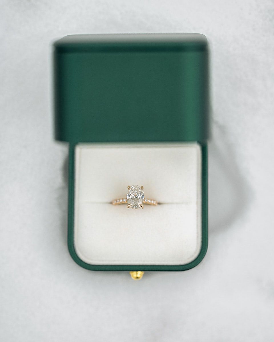 Diamond wedding ring in green ring box in snow, winter engagement detail