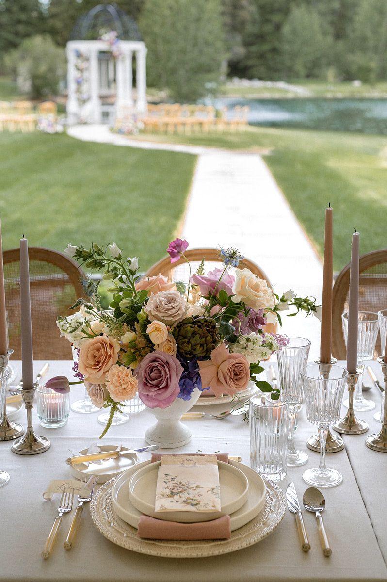 Soft pastel wedding table setting with plates, forks, glasses, and delicate florals