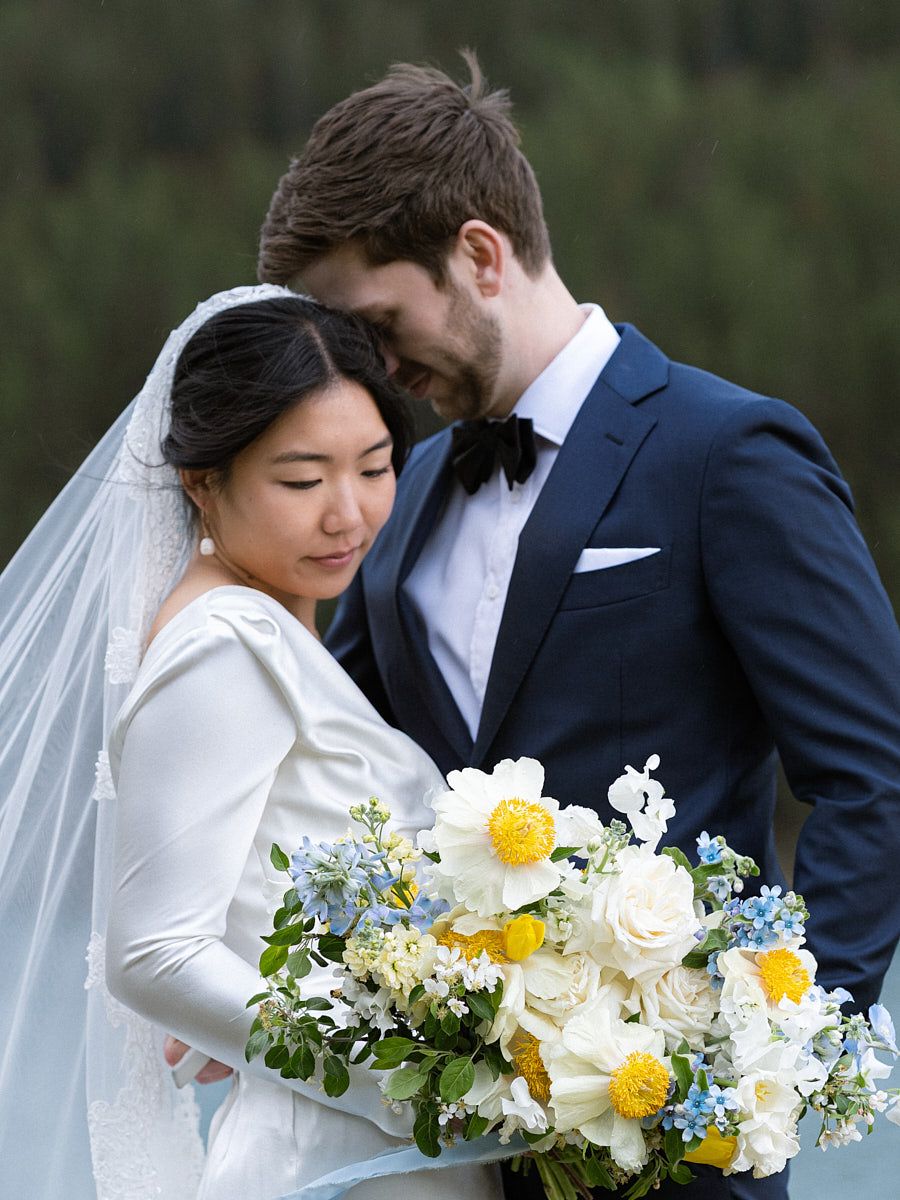 Elegant bride and groom posing by a lake in a European forest setting