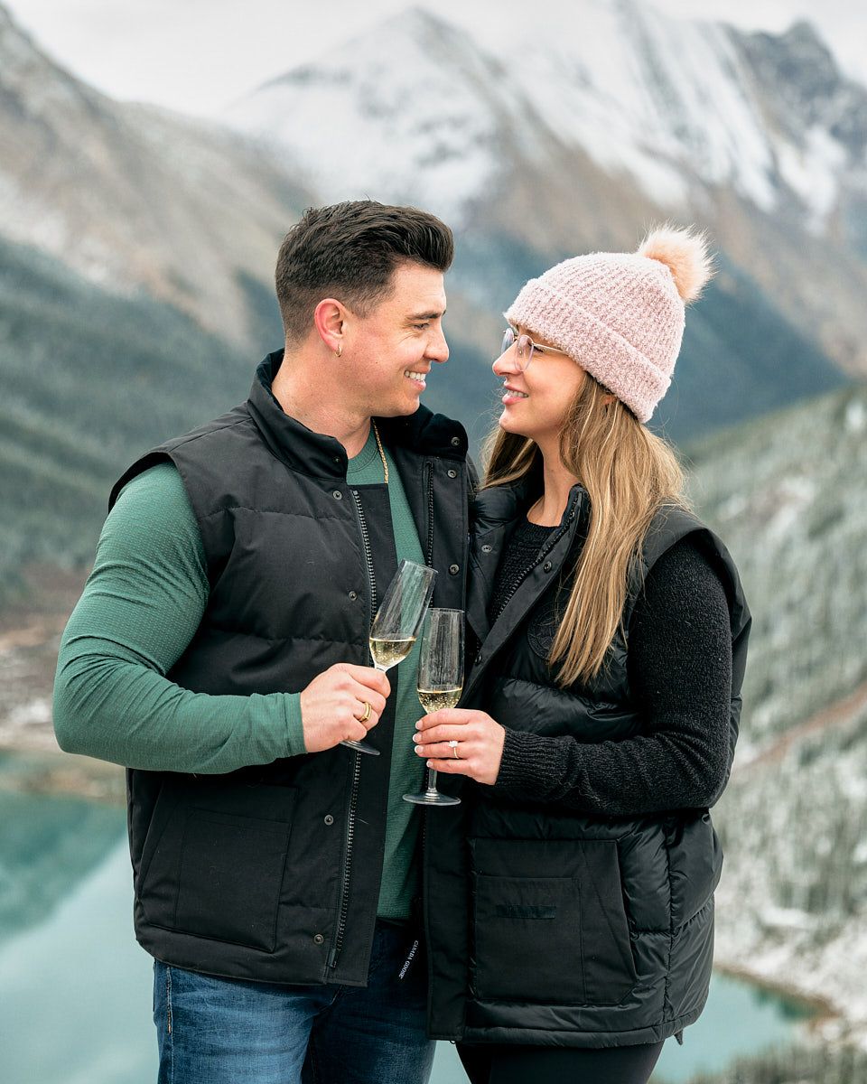 Engaged couple celebrating with champagne in the mountains, romantic Europe engagement shoot