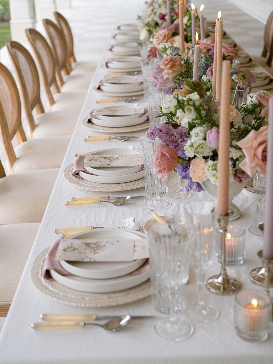 Pastel-themed wedding table arrangement with fine cutlery and floral centerpieces