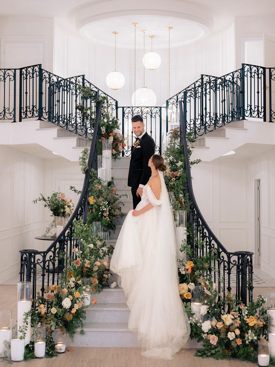 Bride and groom embracing on flower-adorned stairs, elegant Riga wedding moment