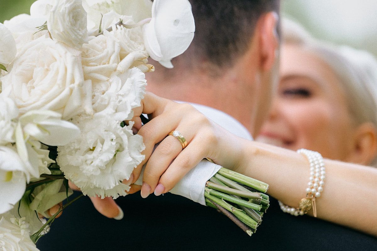 The bride and groom share an intimate embrace on the scenic grounds of Latvia
