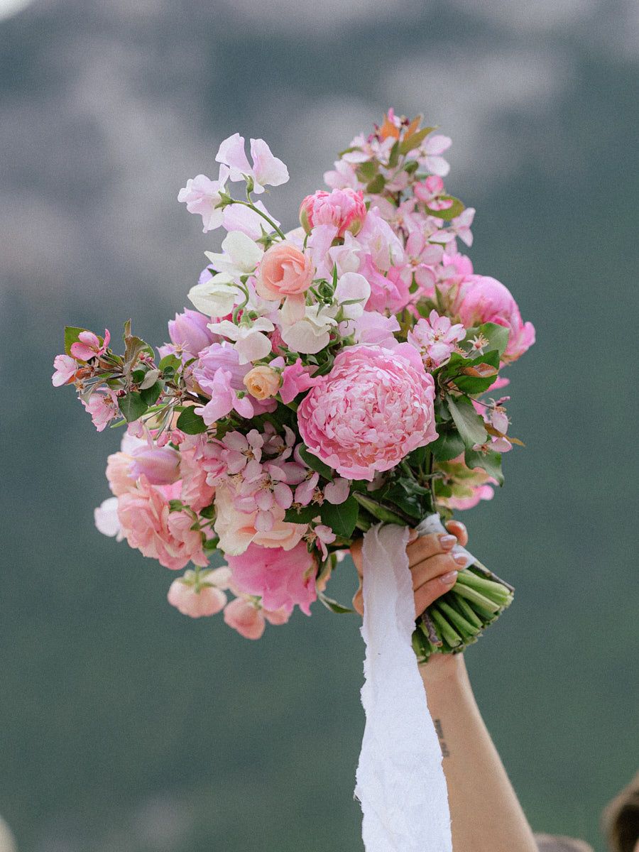 Joyful bride lifting pink bouquet, celebrating wedding day in Riga or European setting
