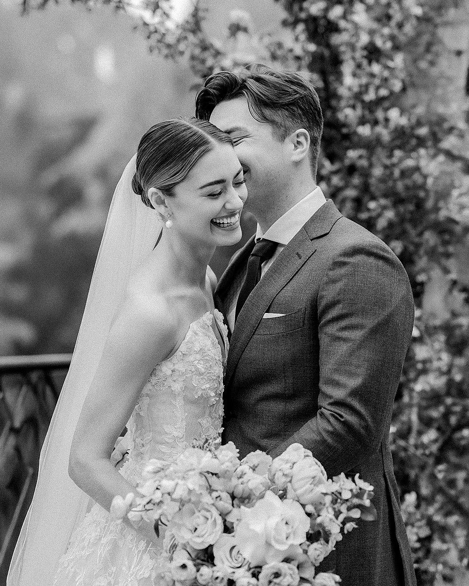 Bride laughing as groom whispers, capturing joyful and candid Riga wedding moments