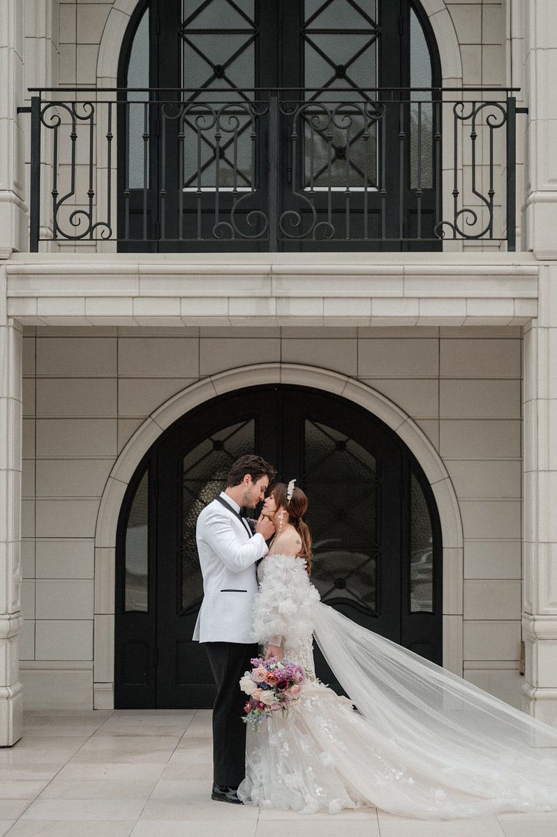 Romantic kiss between bride and groom in front of a historic manor, ideal for Riga wedding photography