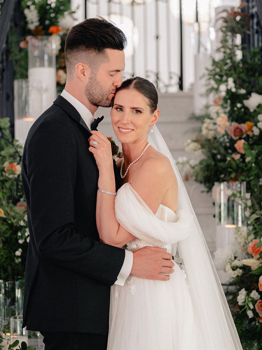 Elegant couple on Riga stairs adorned with flowers, capturing wedding day romance