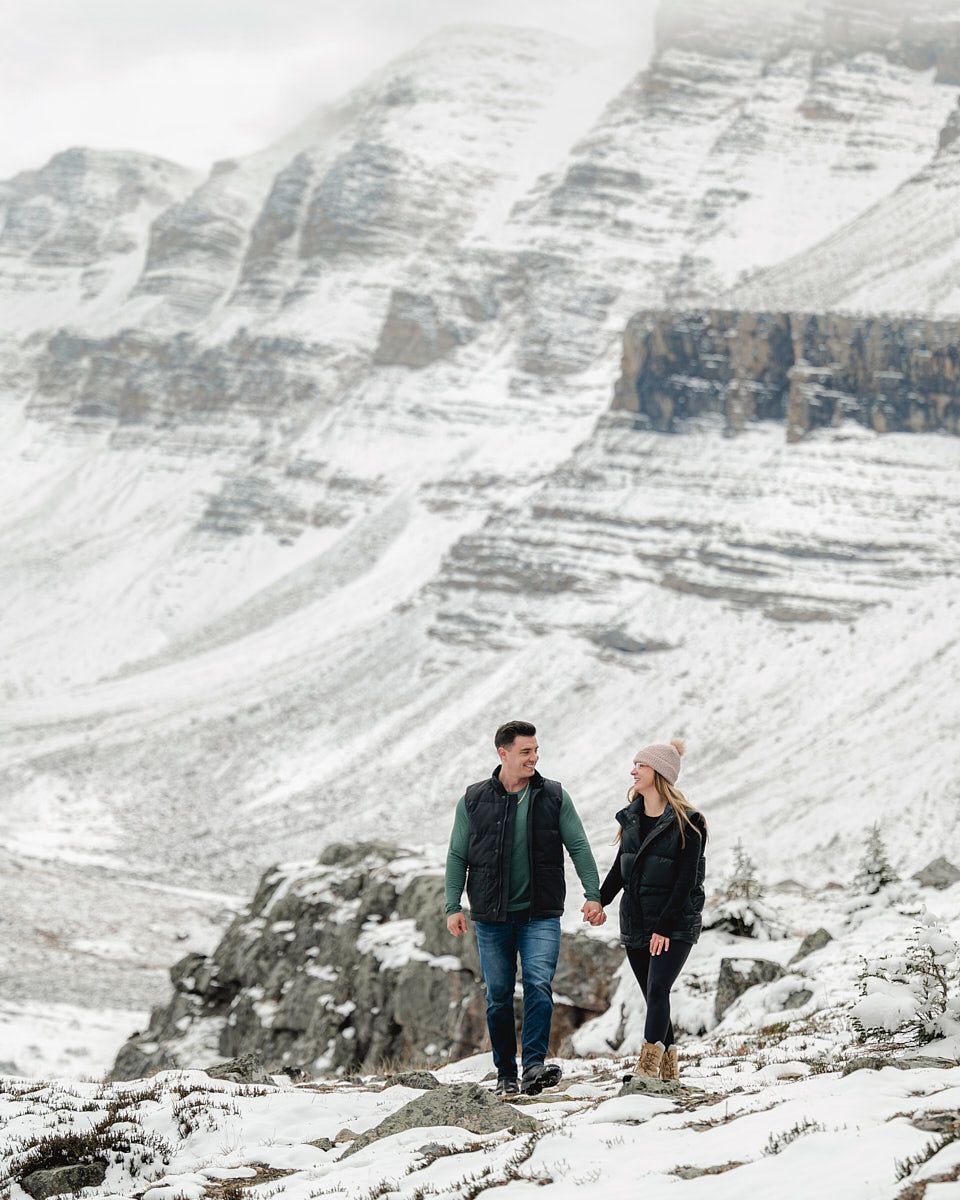 Engaged couple walking through snowy landscape, winter engagement session in Europe