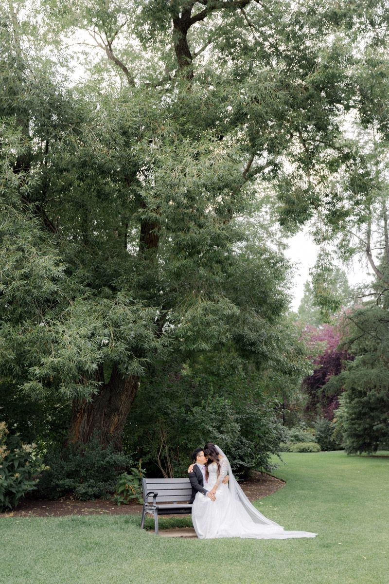 Bride and groom sitting among lush greenery, natural wedding portrait in Riga