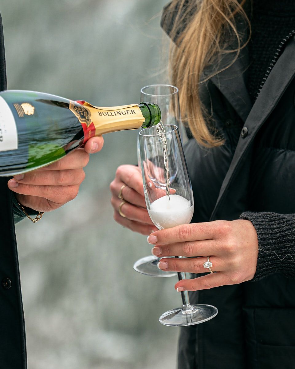 Engaged couple celebrating with champagne in the mountains, romantic Europe engagement shoot