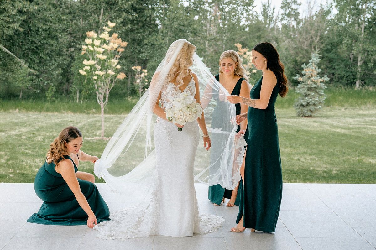 Bridesmaids are adjust bride's veil before the ceremony at the patio at a Latvian wedding venue