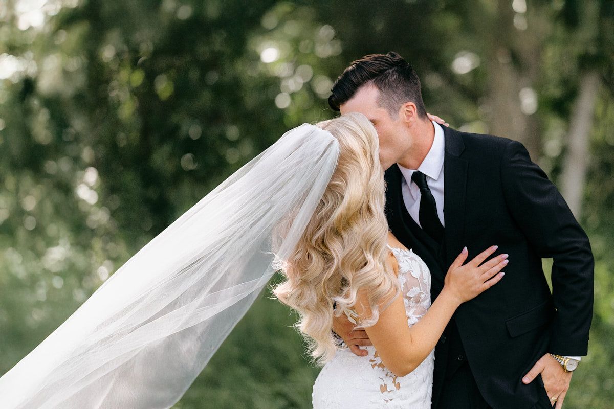 Romantic couple dip kissing in the lush forests in Riga, surrounded by vibrant greenery.