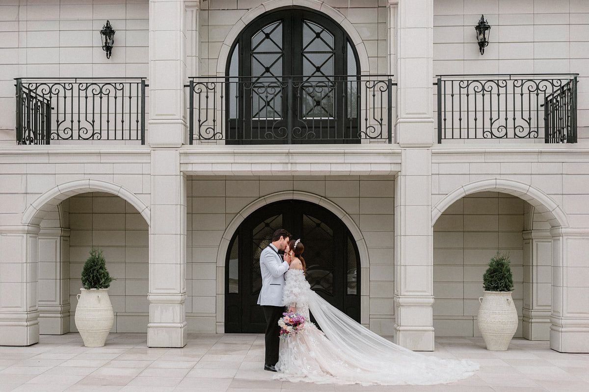 Romantic kiss between bride and groom in front of a historic manor, ideal for Riga wedding photography