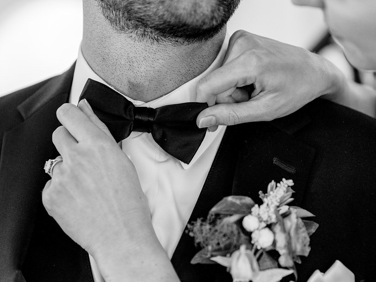 Bride adjusting groom’s bowtie, intimate Riga wedding moment captured in natural light