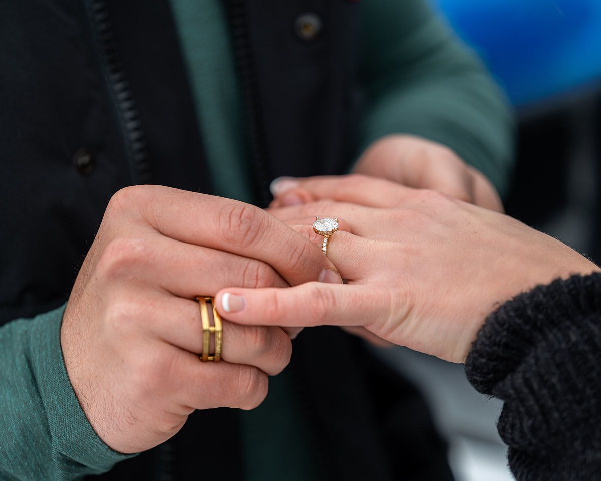 Close-up of engagement ring placed on fiancée’s finger, emotional proposal moment
