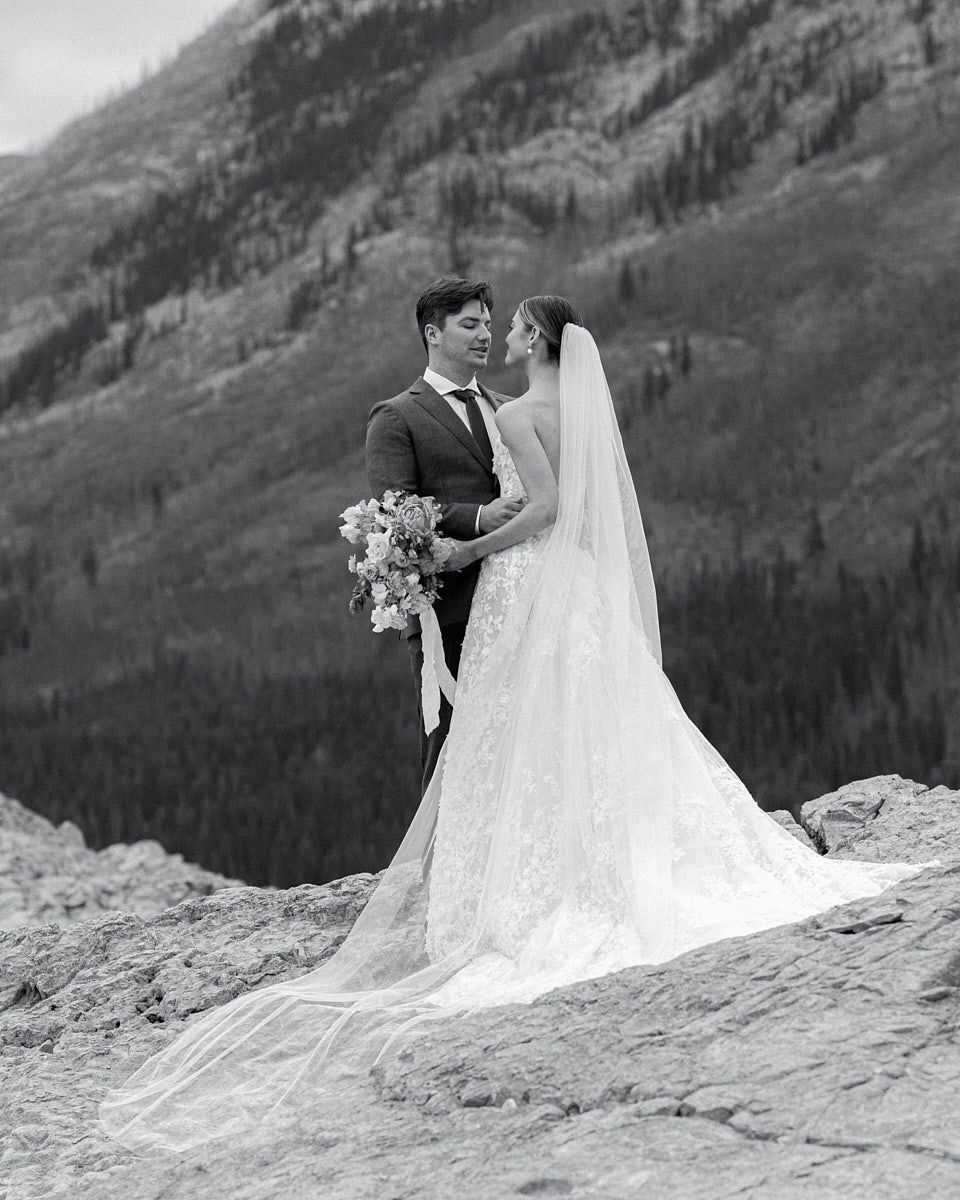 Natural light wedding portrait of bride and groom by a tranquil mountain lake