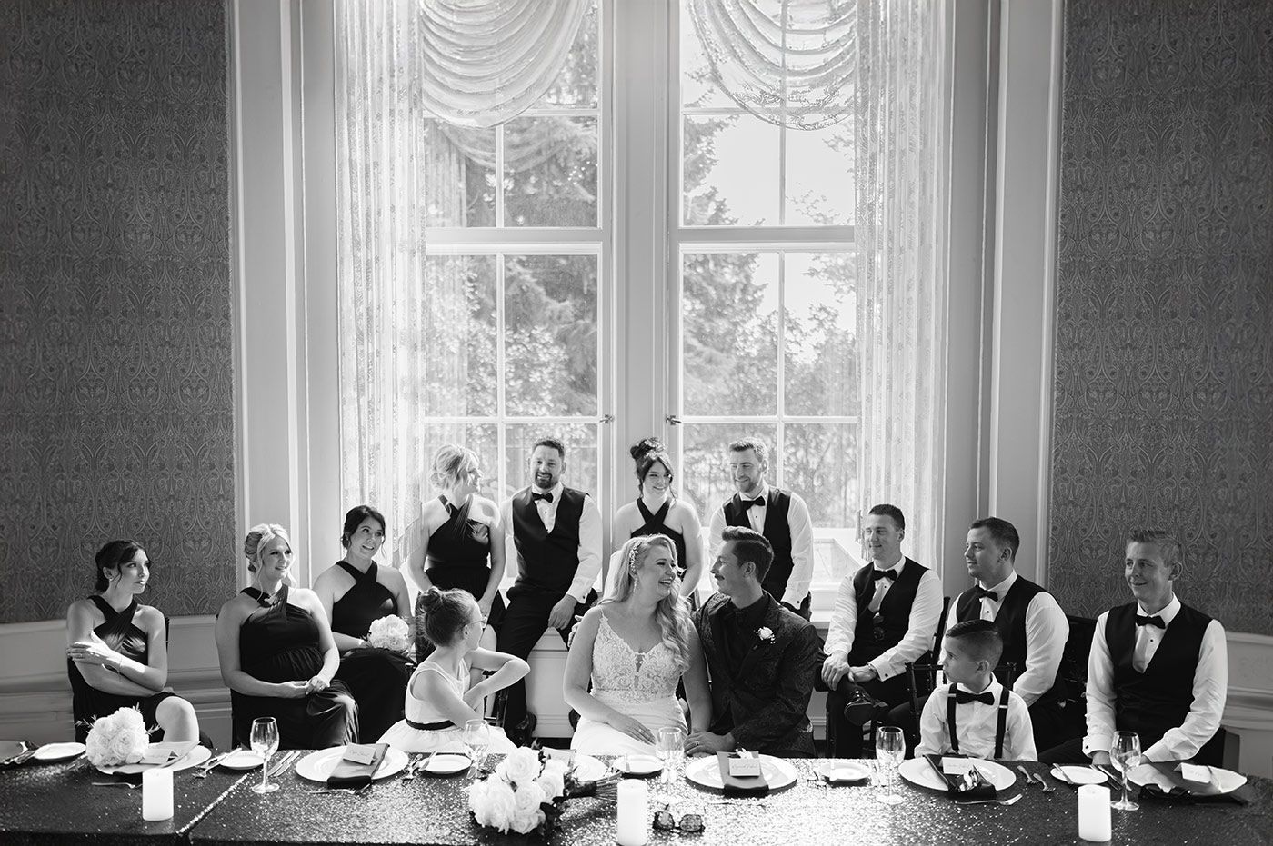 Bride and groom seated with wedding party at reception table in Riga