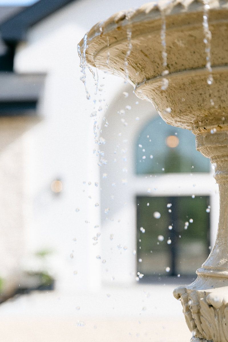 Romantic Latvian wedding venue viewed through fountain, capturing Baltic light and outdoor ceremony ambiance