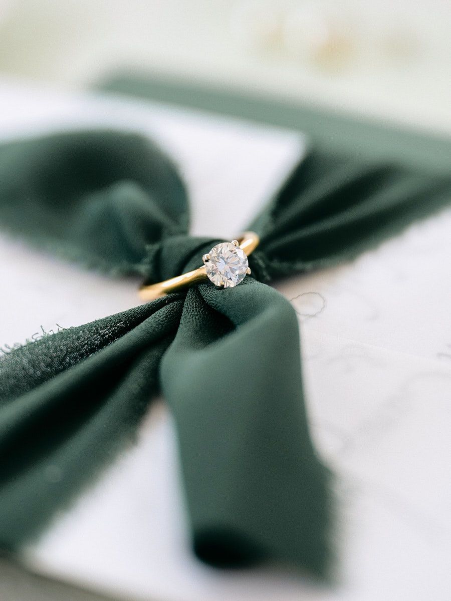 Wedding invitations and a ring styled with lush greenery for a romantic flat-lay at a Latvian wedding venue