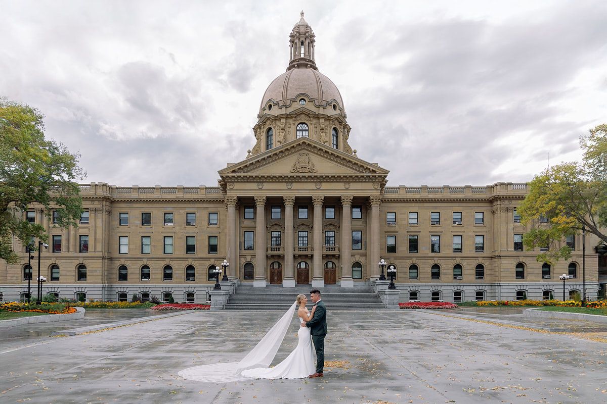 Bride and groom posing in front of grand columned building in Riga