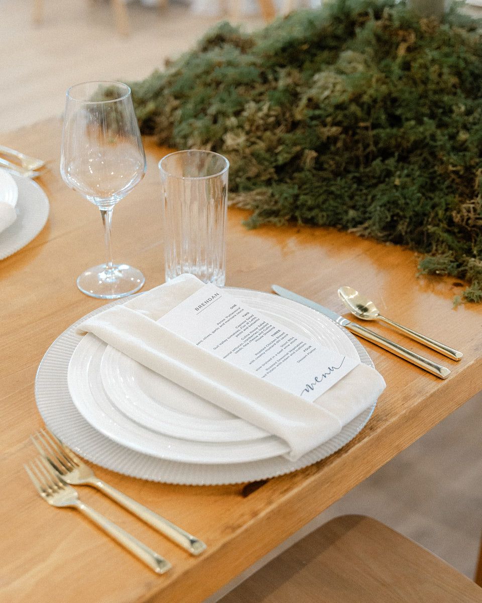 Elegant wedding table setting with plate, utensils, and green floral decor, ideal for Riga receptions