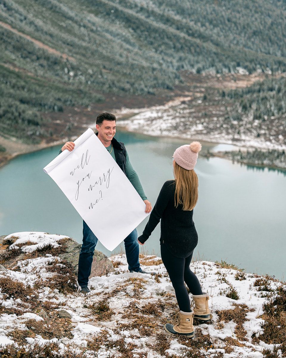 Proposal with “Will you marry me” scroll in scenic mountain engagement session in Europe