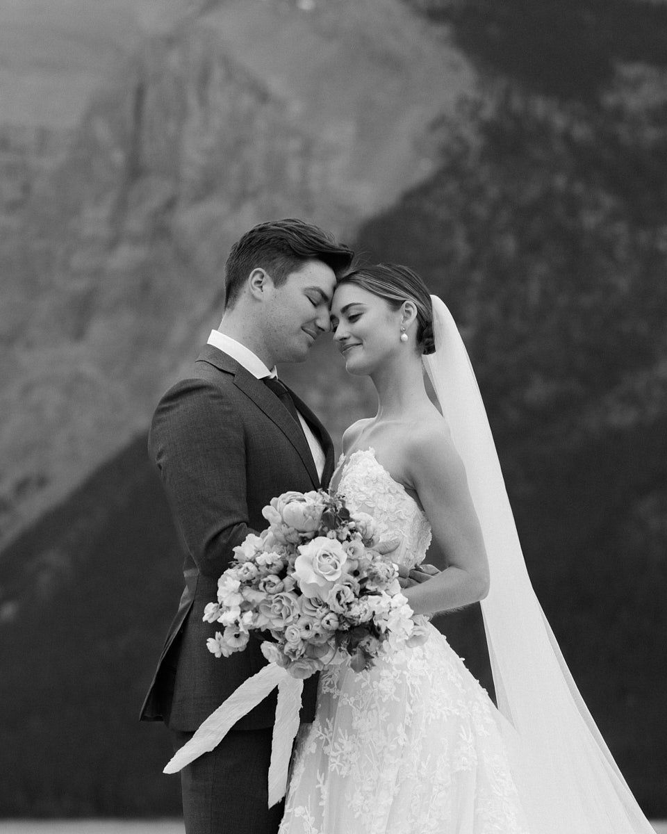 Elegant couple posing by a serene lake in the European mountains for wedding portraits