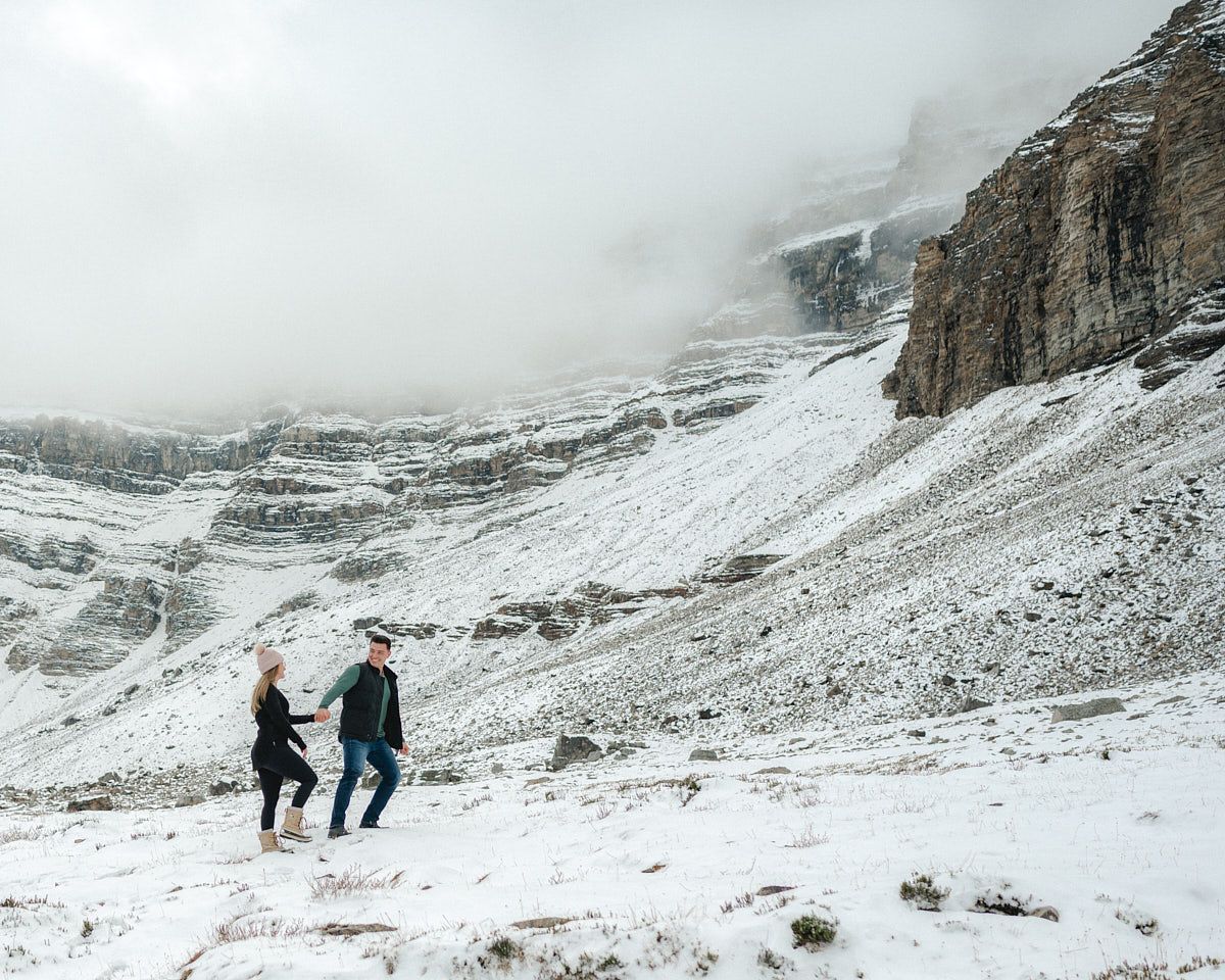 Engaged couple walking through snowy landscape, winter engagement session in Europe