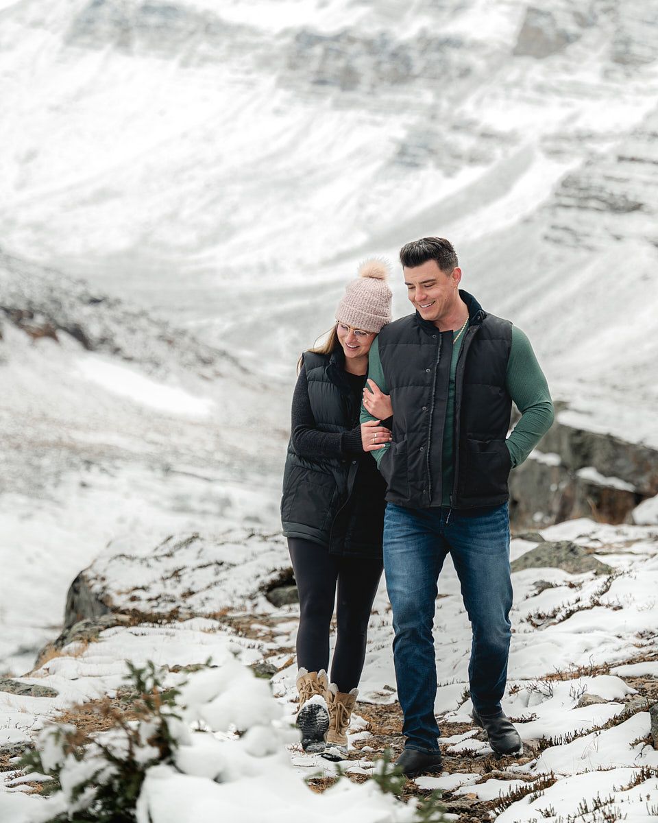 Engaged couple walking through snowy landscape, winter engagement session in Europe