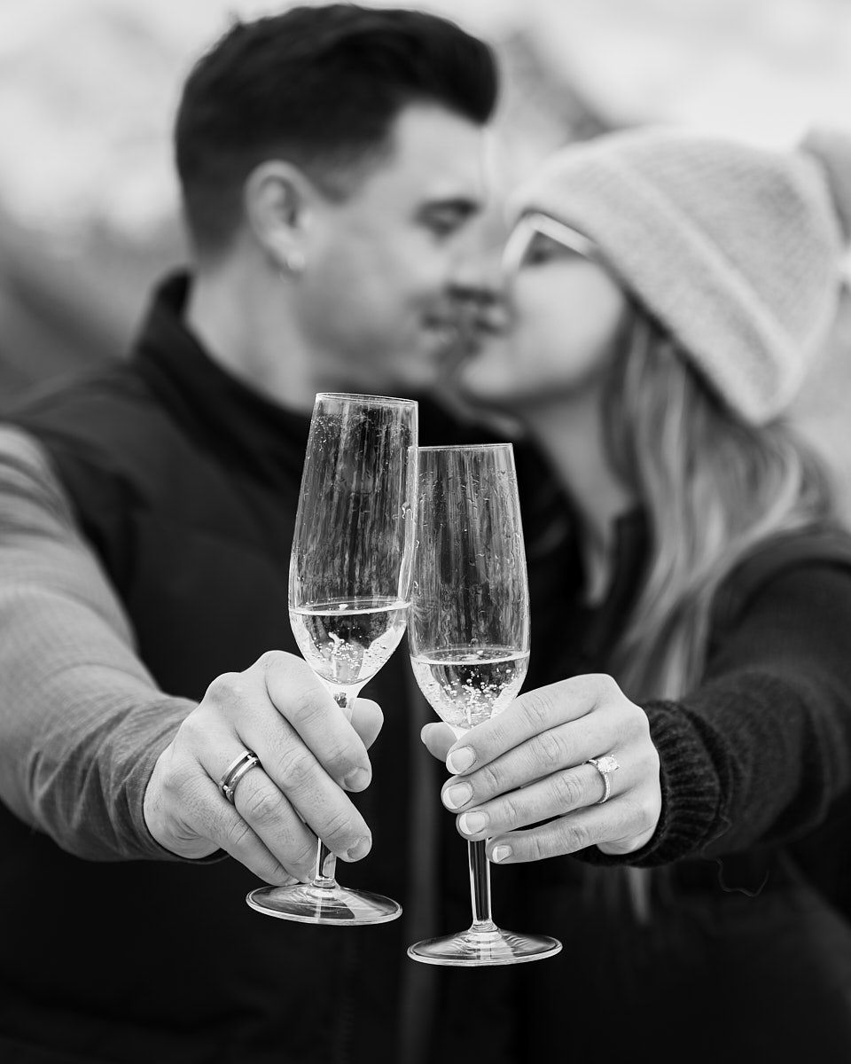 Engaged couple celebrating with champagne in the mountains, romantic Europe engagement shoot