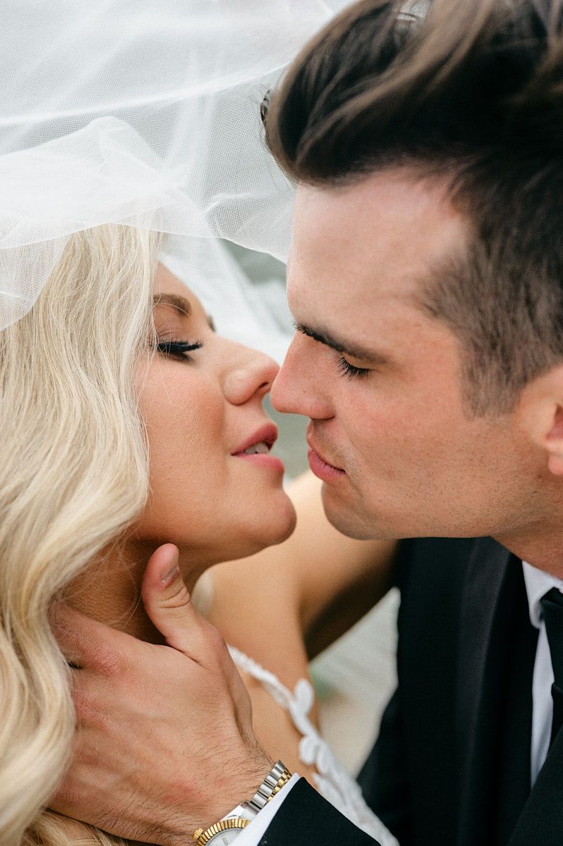 The couple shares a loving glance while standing in front of the grand arched doors at Latvian venue