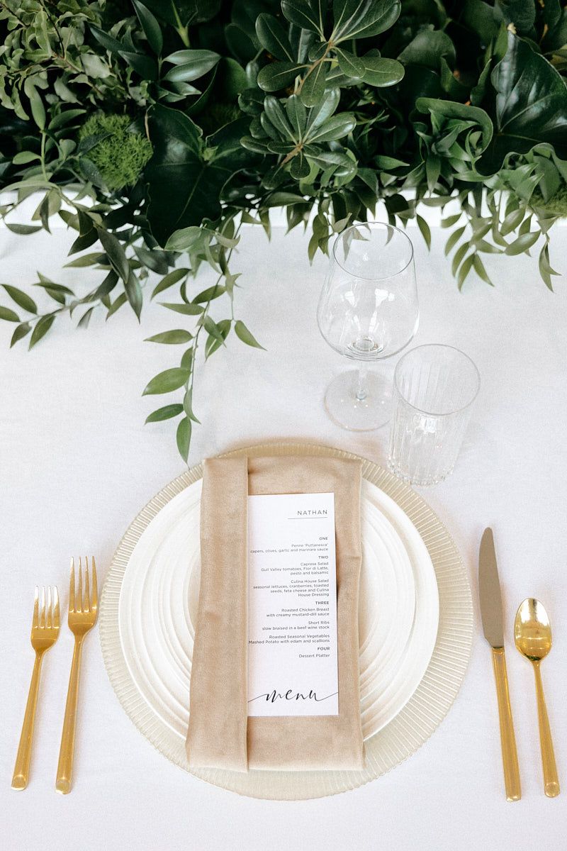 Elegant wedding table setting with plate, utensils, and green floral decor, ideal for Riga receptions