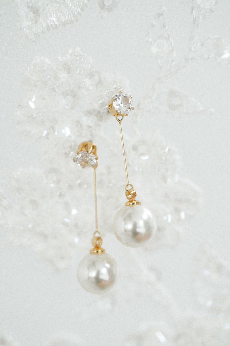 Elegant bridal earrings resting on delicate veil, Riga wedding accessory detail