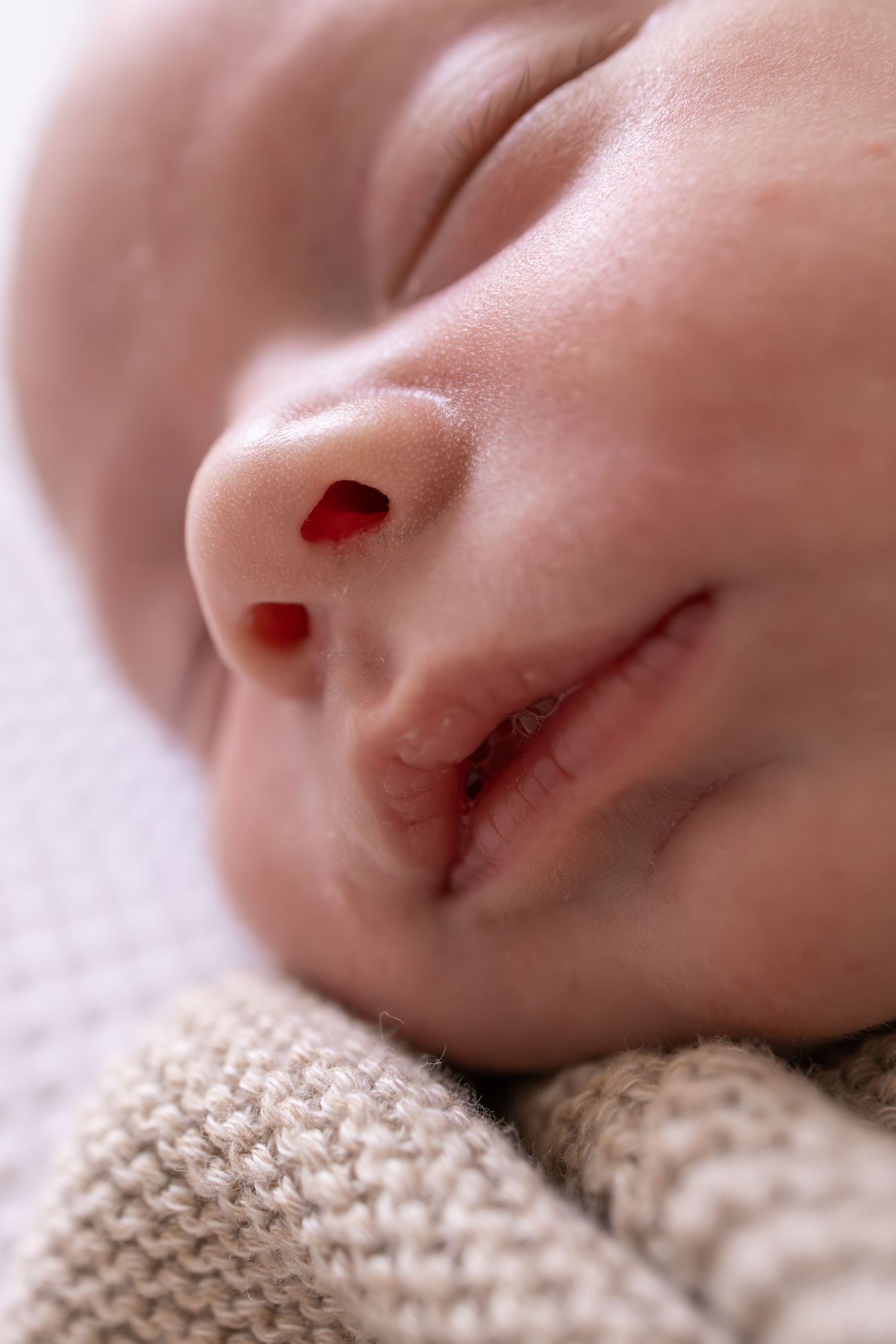 Close-up series showing a sleeping newborn's delicate features against a knit blanket.