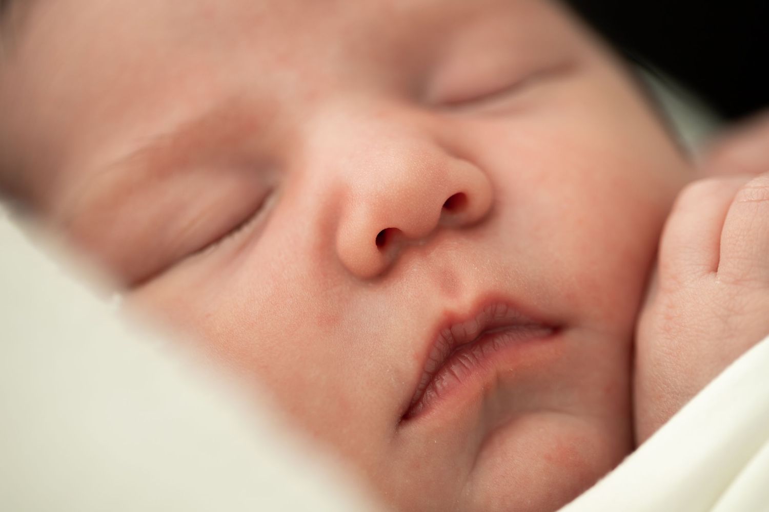 Detailed close-up shots of sleeping newborn's features.