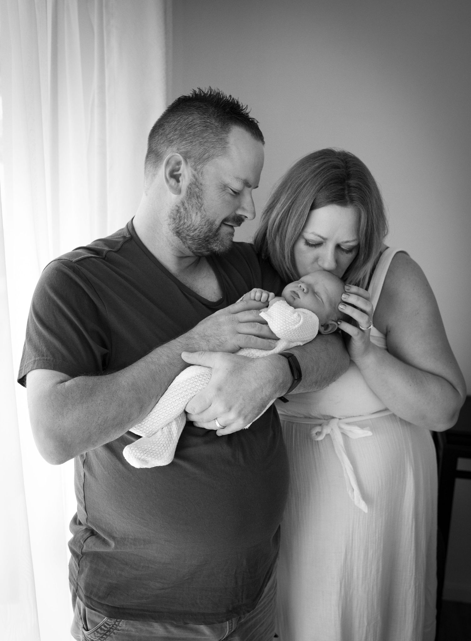 Intimate black and white portrait of new parents with newborn baby.