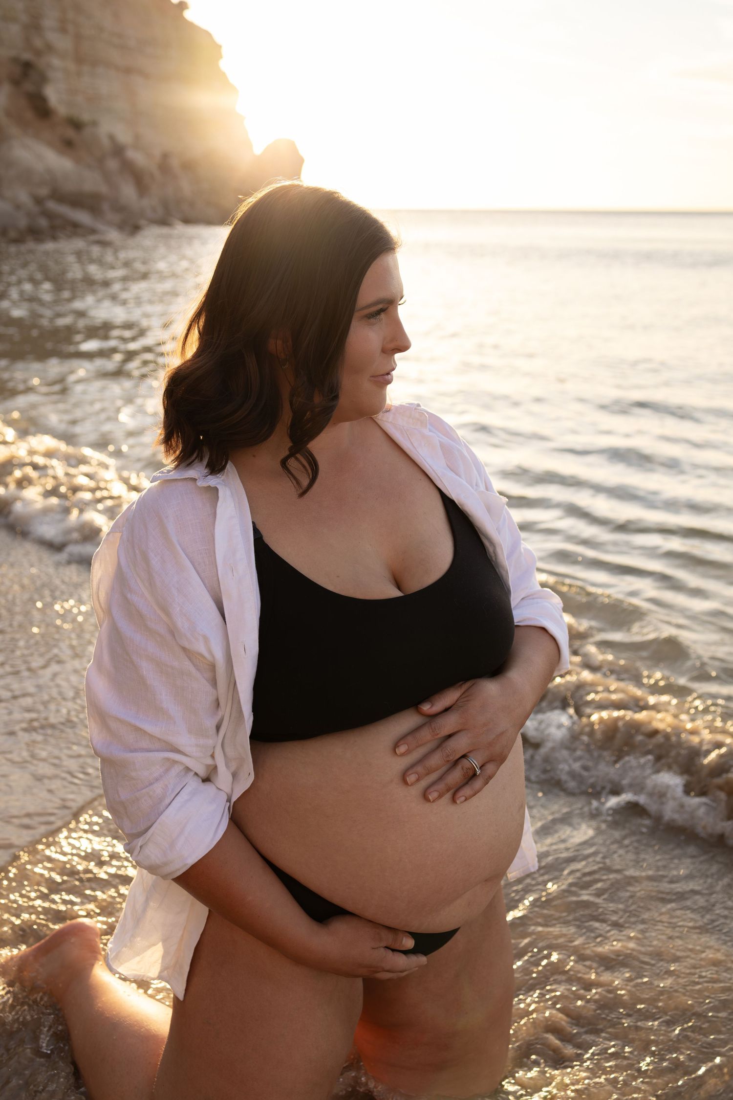 Romantic maternity photos taken at golden hour by the ocean.