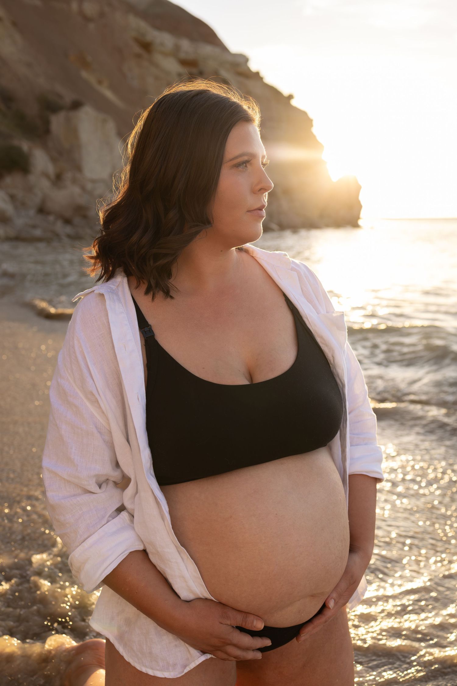 Maternity beach portraits with white button-down shirt and black underwear at golden hour.